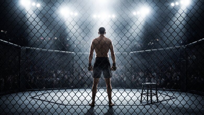 Bojovník v MMA klietke pod svetlami arény, pohľad zboku cez pletivo